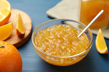 Delicious orange marmalade in bowl on blue wooden table