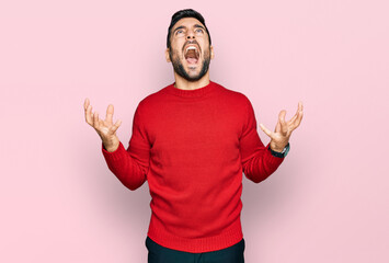 Young hispanic man wearing casual clothes crazy and mad shouting and yelling with aggressive...