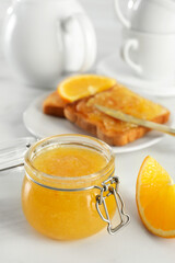 Delicious orange marmalade and citrus fruit slice on white table. Space for text