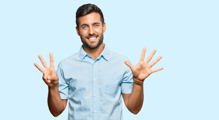 Fototapeta premium Handsome hispanic man wearing casual clothes showing and pointing up with fingers number eight while smiling confident and happy.