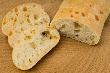 Ciabatta - Italian bread with cheese cut into slices on a wooden board
