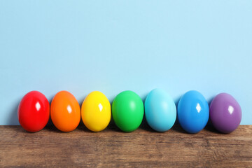 Easter eggs on wooden table against light blue background, space for text