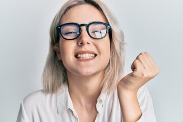 Young blonde girl wearing casual clothes and glasses screaming proud, celebrating victory and...
