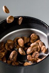 Coffee beans flying over the electric coffee grinder.