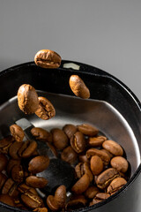Coffee beans flying over the electric coffee grinder.