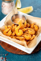 Fried shrimps in a white plate on a blue background