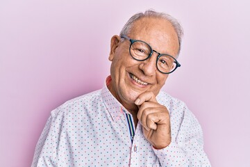 Senior caucasian man wearing casual clothes and glasses smiling looking confident at the camera with crossed arms and hand on chin. thinking positive.