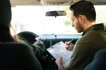 Male instructor checking the driving skills of a teen girl