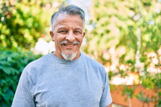Middle age hispanic grey-haired man smiling happy standing at the park.