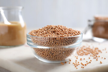 Mustard seeds in glass bowl on board, closeup.