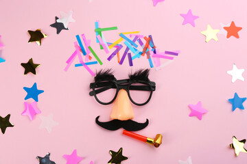 Clown face, confetti and party horn on pink background, flat lay