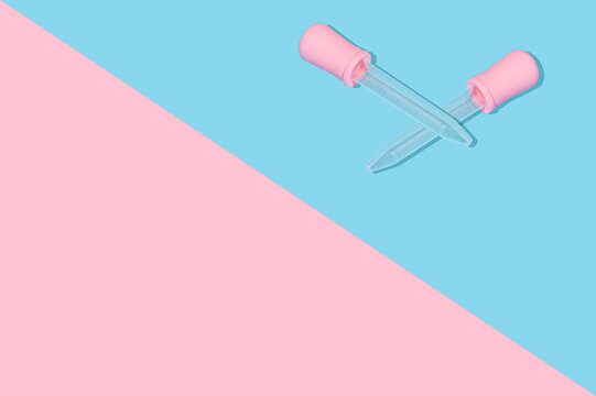 Medical pipettes for liquids and medicines lie cross on cross Pattern for design. On partially blue and pink. Copy space © Fotostockerspb