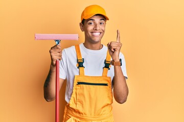 Young handsome african american man window cleaner holding glass washer smiling with an idea or question pointing finger with happy face, number one