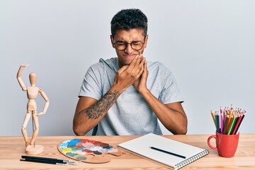 Young handsome african american man painter sitting palette and art manikin touching mouth with hand with painful expression because of toothache or dental illness on teeth. dentist