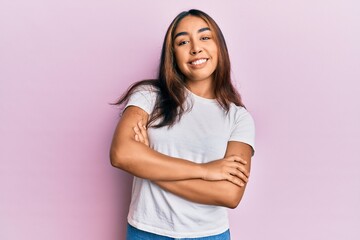 Young latin woman wearing casual white tshirt happy face smiling with crossed arms looking at the camera. positive person.