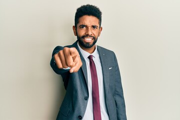 Handsome hispanic man with beard wearing business suit and tie pointing displeased and frustrated to the camera, angry and furious with you