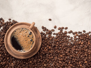 Roasted coffee beans lying on a white plate with a cup of coffee. Top view, place for tex, copy space.