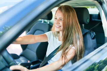 Fototapeta na wymiar Young beautiful blonde woman smiling happy driving car