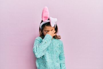 Little beautiful girl wearing cute easter bunny ears tired rubbing nose and eyes feeling fatigue and headache. stress and frustration concept.
