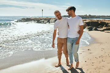 Young gay couple smiling happy walking at the beach.