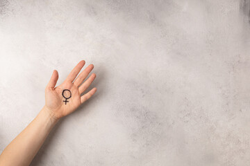 Female hand with female symbol of Venus on grey background for international womens day