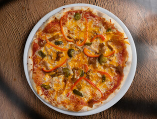 Spicy pizza on a thin dough with bell pepper, jalapeno pepper, onion and cheese