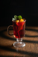 Hot fruit tea with orange, mint and cinnamon in a clear glass