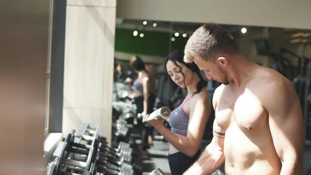 Sports people are engaged with dumbbells in the gym.