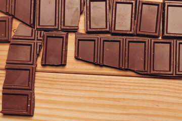 broken bar of chocolate on wooden background top view texture sweets candy