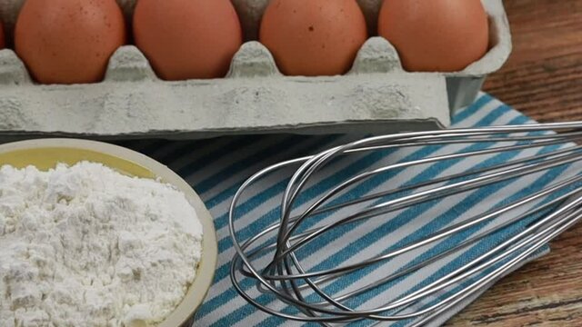 bo&icirc;te d'oeufs, farine et fouet de cuisine sur une table