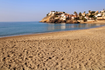 Obraz premium Playa de Bolnuevo, en Mazarrón (Murcia-España). Arena de la playa y superficie del mar en calma, con algunas casas junto al Mediterráneo.