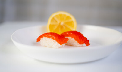 side view, white plate with sushi and lemon on a white background, red fish on rice