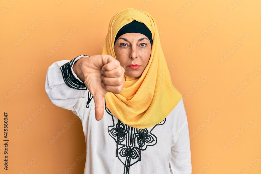 Poster middle age hispanic woman wearing traditional islamic hijab scarf looking unhappy and angry showing 