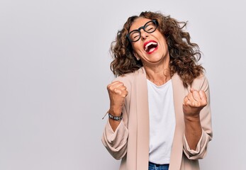 Middle age beautiful businesswoman wearing glasses standing over isolated white background celebrating surprised and amazed for success with arms raised and eyes closed