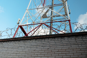 Telecommunication tower against the blue sky, with barbed wire. TV tower. Forbidden zone