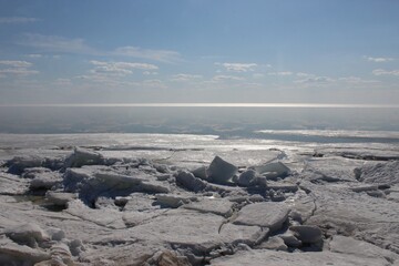 Aerial abstract melting ice on sea. The sunlit horizon line with cloud reflexes in the water