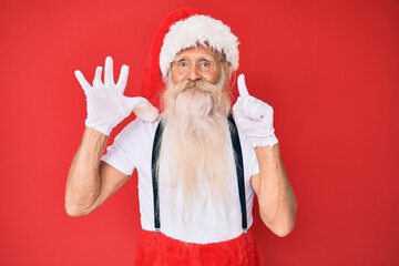 Old senior man with grey hair and long beard wearing white t-shirt and santa claus costume showing and pointing up with fingers number six while smiling confident and happy.