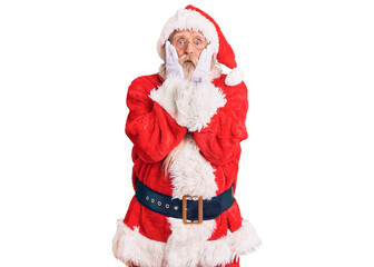 Old senior man with grey hair and long beard wearing traditional santa claus costume afraid and shocked, surprise and amazed expression with hands on face