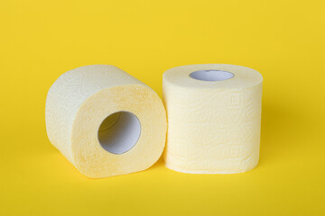 Two rolls of toilet paper on a yellow background. Personal hygiene concept.