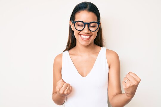 Young beautiful latin girl wearing casual clothes and glasses celebrating surprised and amazed for success with arms raised and eyes closed