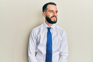 Young man with beard wearing business tie looking away to side with smile on face, natural expression. laughing confident.