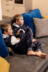 Obraz premium the little brothers in kigurumi watching tv at home