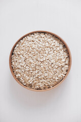 Dry oatmeal in a wooden bowl on a white background. Top view. Copy, empty space for text