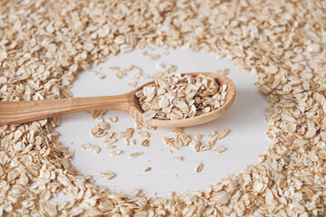 Uncooked oatmeal in a wooden spoon on a white background. Copy, empty space for text