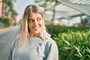 Young blonde girl smiling happy standing at the park