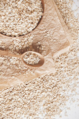 Uncooked oatmeal in a wooden bowl and spoon on kraft paper background. Top view. Copy, empty space for text