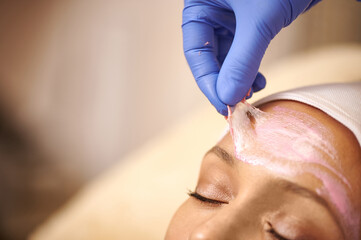 Removing the mask after cleansing the face. Close-up. The esthetician removes the cosmetic mask from the face of a relaxed client