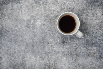 A cup of black coffee on gray concrete table.