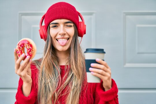 Young hispanic woman having breakfast using headphones at the city.