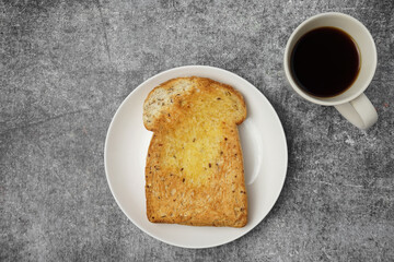 Baked whole grain bread with butter and a cup of black coffee.
